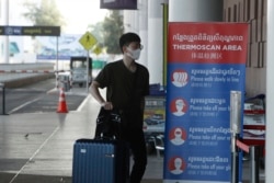 FILE - A tourist wearing a face mask enters an area of thermo scan at the quiet Phnom Penh International Airport in Phnom Penh, April 3, 2020.