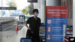 FILE - A tourist wearing a face mask enters an area of thermo scan at the quiet Phnom Penh International Airport in Phnom Penh, Cambodia, Friday, April 3, 2020. 
