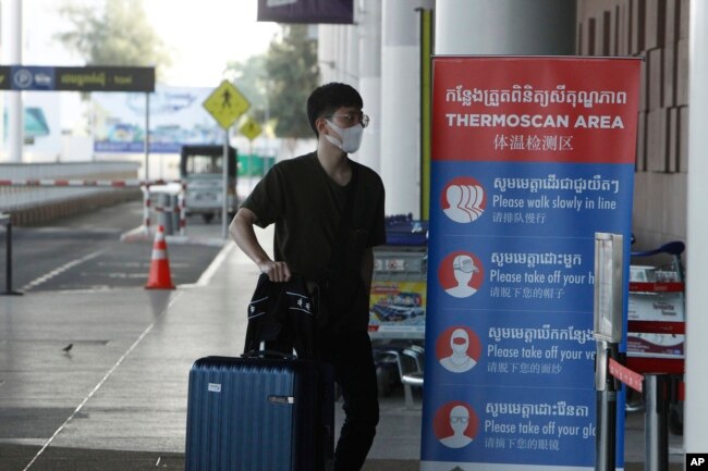 FILE - A tourist wearing a face mask enters an area of thermo scan at the quiet Phnom Penh International Airport in Phnom Penh, April 3, 2020.