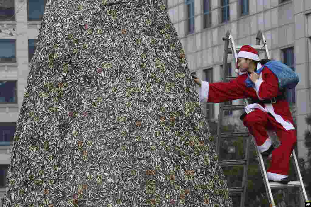 A member of Korean Federation for Environmental Movement in a Santa Claus outfit attaches dumped cigarette butts at a cigarette butt Christmas tree in front of Korea Tobacco &amp; Ginseng Corporation office in Seoul, South Korea.