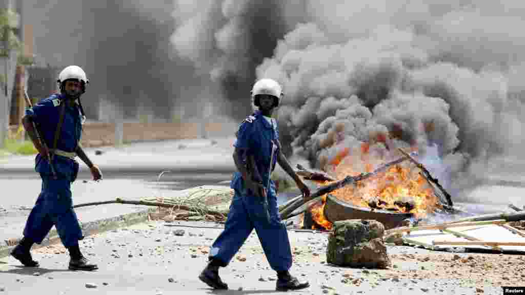 Policemen walk in front of burned barricade during a protest against Burundian President Pierre Nkurunziza's decision to run for a third term in Bujumbura, Burundi, May 13, 2015.
