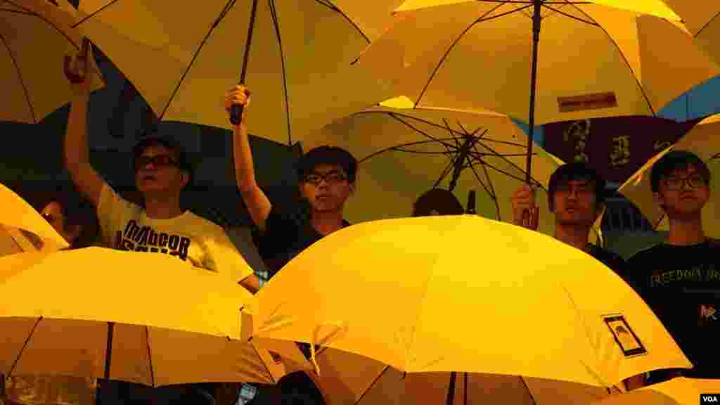 黄之峰（左二）和周永康（左）和其他人在集会上打开雨伞纪念占中满月（美国之音/伊万&middot;布罗德黑德） 