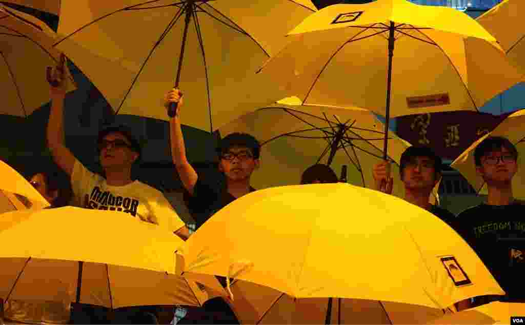 Joshua Wong (tengah, kiri) dan Alex Chow bergabung bersama para pemimpin gerakan payung &quot;Umbrella Movement&quot; dalam mengembangkan payung mereka dalam demonstrasi yang memperingati satu bulan sejak dimulainya protes-protes di Hong Kong.&nbsp;(VOA/Ivan Broadhead). 