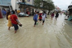 Garment workers walk through the flood waters following recent rains as they head home after their work at Kambol village, outside Phnom Penh, Cambodia, Tuesday, October 20, 2020. AP Photo/Heng Sinith