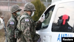 戴著口罩的韓國士兵在大邱的一個軍營哨卡檢查一輛救護車。 （2020年2月26日）