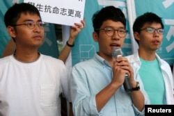 FILE - Newly elected lawmaker Nathan Law (C), student leaders Joshua Wong (R) and Alex Chow meet journalists outside a court before a hearing as prosecutors asked them to be jailed immediately over their roles in storming government headquarters in 2014.