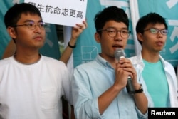 Newly elected lawmaker Nathan Law (C), student leaders Joshua Wong (R) and Alex Chow meet journalists outside a court before a hearing.