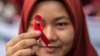 Seorang pelajar menunjukkan pita merah saat kampanye Hari AIDS Sedunia di Medan, Sumatra Utara, 2 Desember 2018. (Foto: AFP)