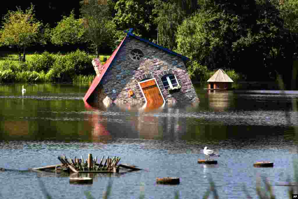 An art installation, a &#39;sunken&#39; house, is photographed in the pond of the&#39; Kunsthalle Rostock&#39; museum in Rostock, Germany. The installation &#39;Atlantis&#39; by Tea Makipaa is part of the exhibition &#39;Nature and More&#39; with contemporary art from Finland, that will run until Sept. 14, 2014.