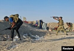 Iraqi security forces fire their weapons during clashes with Islamic State militants on the outskirts of Ramadi, June 15, 2015.