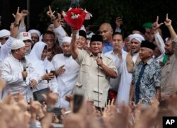 Calon presiden Prabowo Subianto, tengah, mengangkat karangan bunga yang diterimanya dari seorang pendukung di Jakarta, Jumat, 19 April 2019. (Foto: AP)