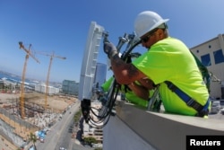 FILE - Telecommunications workers Chris Viens and Guy Glover install a new 5G antenna system made by Ericsson for AT&T's 5G wireless network in downtown San Diego, California, U.S., April 23, 2019.