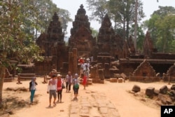 In this April 15, 2016, photo, tourist visit the Banteay Srey temple of the Angkor complex. The Angkor Wat temple is now off-limits to cars as authorities seek to ease traffic jams at the site that draws millions of tourists a year.
