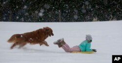 Una niña juega con su perro en la nieve en el estado de Carolina del Sur. Enero 3 de 2017.