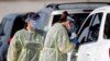 Healthcare workers conducts COVID-19 tests at a drive-thru coronavirus testing site, Tuesday, April 21, 2020, in Sanford, Fla. (AP Photo/John Raoux)