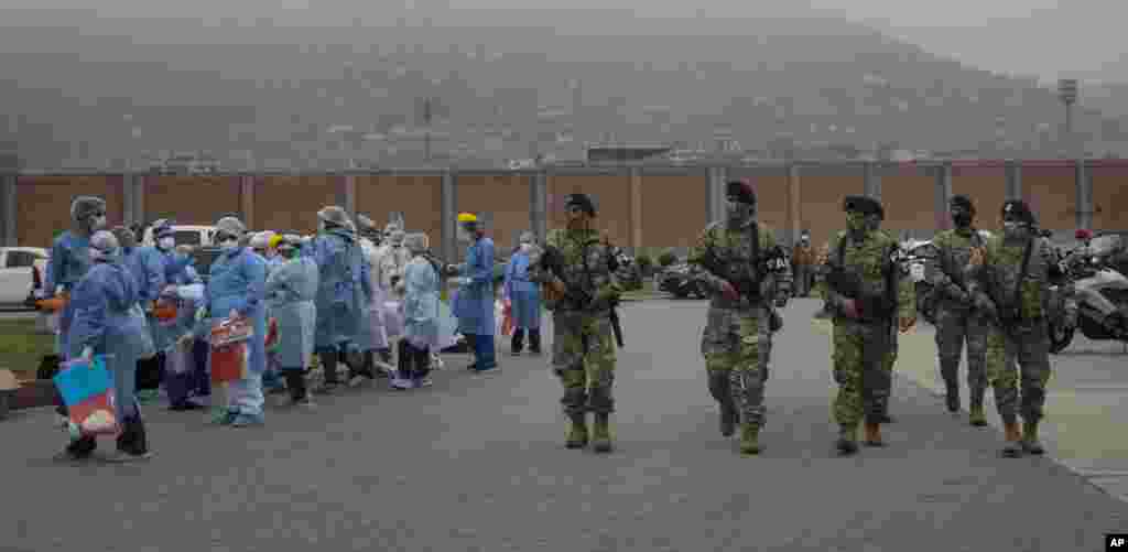 Soldiers provide security as doctors and nurses prepare to do house-to-house coronavirus testing in Villa el Salvador, on the outskirts of Lima, Peru.