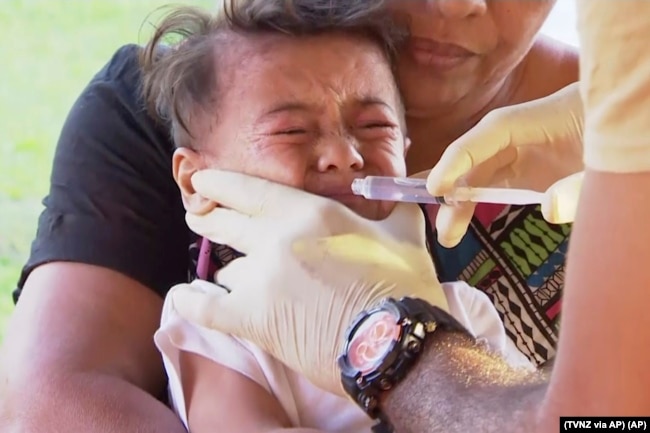In this November 2019, image from video, a child gets vaccinated against measles at a health clinic in Apia, Samoa.