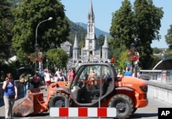 Authority blocks with a bulldozer one of the entries to the site of the sanctuary in Lourdes, southwestern France, Aug.14, 2016