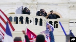 FILE - Supporters loyal to then-President Donald Trump challenge authorities before successfully breaching the Capitol building during a riot on its grounds, Jan. 6, 2021.