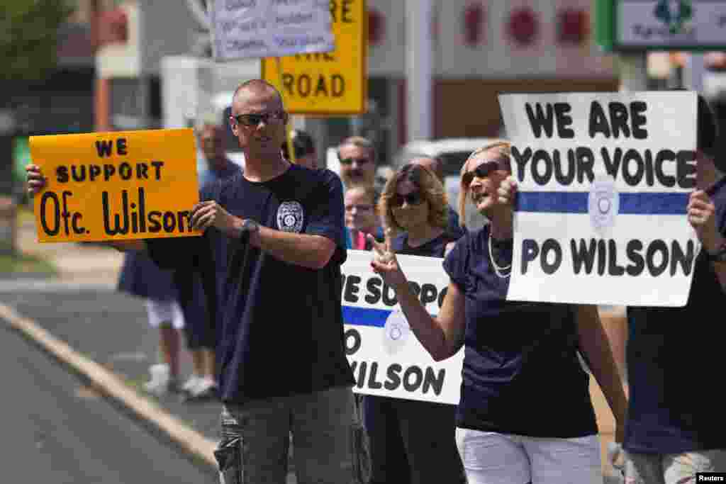 Supporters of officer Darren Wilson hold posters outside Barney's Sports Pub in St. Louis, Missouri, Aug. 23, 2014.