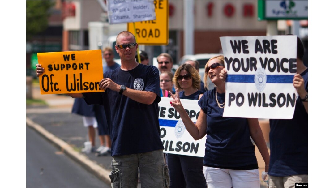 FILE - Supporters of Officer Darren Wilson hold posters outside Barney's Sports Pub in St. Louis, Missouri, Aug. 23, 2014.