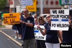 Supporters of officer Darren Wilson hold posters outside Barney's Sports Pub in St. Louis, Missouri, Aug. 23, 2014.