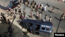 Paramilitary soldiers and police officers gather at the site of a bomb blast in Karachi, June 26, 2013.