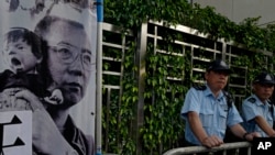 Police officers stand guards next to a portrait of jailed Chinese Nobel Peace laureate Liu Xiaobo during a demonstration outside the Chinese liaison office in Hong Kong, July 10, 2017.