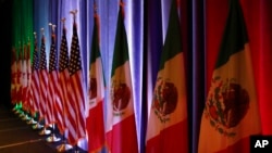 FILE - From left, the national flags of Canada, the U.S. and Mexico are illuminated by stage lights ahead of a news conference at the start of trilateral trade talks in Washington, Aug. 16, 2017. 
