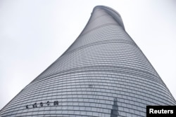 FILE - Workers clean the exterior of skyscraper Shanghai Tower at the financial district of Pudong in Shanghai, China. Chinese companies would be able to raise $46 billion annually through the green instrument until 2020 according to Xu Nan.