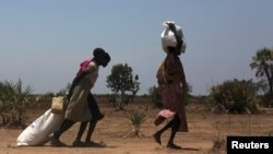 FILE - Women carry food at a food distribution site in Nyal, Unity State, Sudan.
