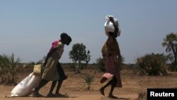 FILE - Women carry food at a food distribution site in Nyal, Unity State. More than one million people have been forced from their homes by the conflict, of which 803,200 have been displaced within South Sudan and 254,600 have fled to neighbouring countr