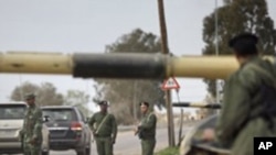 Soldiers and dozens of tanks from the Libyan military's elite Khamis Brigade, led by Gadhafi's youngest son Khamis Gadhafi, take positions and check vehicles after arriving hours earlier on the road in Harshan, 10km east of Zawiya, in Libya, Monday, Feb. 
