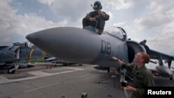 Sgt. Lauren Colantropo (L) and Cpl. Andrew Allen re-install an infrared radar sensor on a fighter jet aboard the amphibious assault ship USS Bonhomme Richard in Subic Bay, Philippines, in this October 7, 2012 handout photo courtesy of the U.S. Navy.