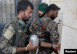 FILE - A Kurdish fighter from the People's Protection Units (YPG) holds an improvised explosive device in Raqqa, Syria, June 16, 2017.