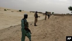 Thành viên nhóm Hồi giáo cực đoan Ansar Dine đứng bảo vệ xung quanh khu vực nơi họ đang chuẩn bị chặt tay của một thanh niên bị kết tội ăn cắp gạo theo luật Sharia ở Timbuktu, Mali. 
