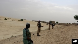 In this Sunday, Sept. 16, 2012 photo, members of Islamist group Ansar Dine stand guard around the area where they are preparing to amputate the hand of a young man found guilty of stealing rice, in Timbuktu, Mali. In a report launched Thursday, Sept. 20, 2012, Amnesty International says it has documented 'horrific abuses' against civilians in Islamist-controlled northern Mali, including the recruitment of child soldiers, sexual violence, extra-judicial executions, and seven amputations just since August. (AP Photo)