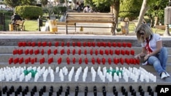 A woman arranges candles with the colors of Syrian national flag during a sit-in for people who were killed during protests in Syria, Damascus, June 29, 2011