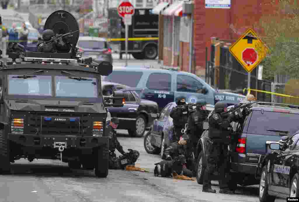 Police officers take position during a search for the Boston Marathon bombing suspects in Watertown, Massachusetts April 19, 2013. Police on Friday killed one suspect in the Boston Marathon bombing during a shootout and mounted a house-to-house search fo