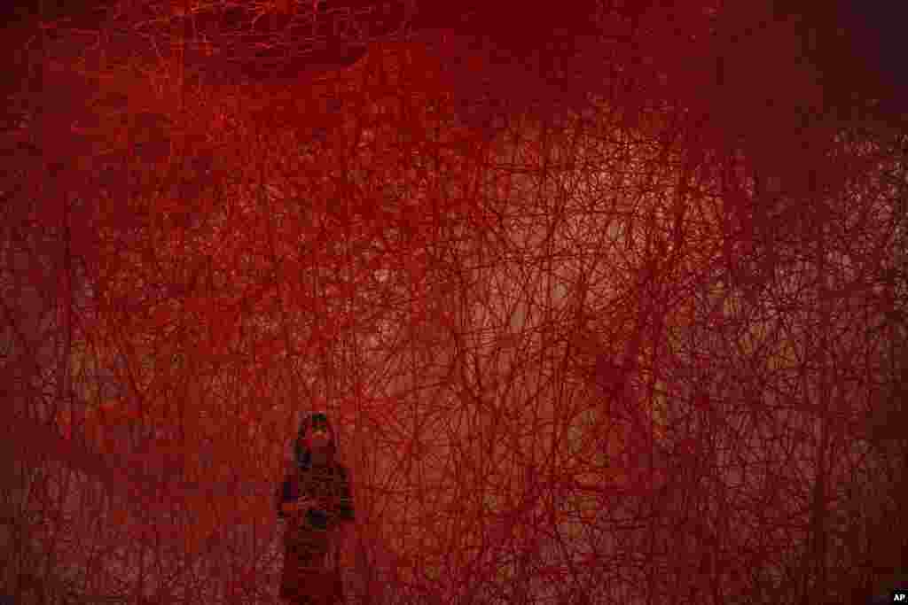 A woman looks at Chiharu Shiota&#39;s art installation titled &quot;Uncertain Journey&quot; at the Mori Art Museum in Tokyo, Japan.