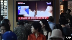 People watch a television news screen showing file footage of North Korea's missile launch, at a railway station in Seoul on August 10, 2019.