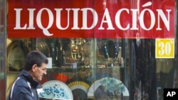 A man walks past a shop selling Spanish fans with a sign reading 'Liquidation' during early sales in Madrid, January 2, 2012