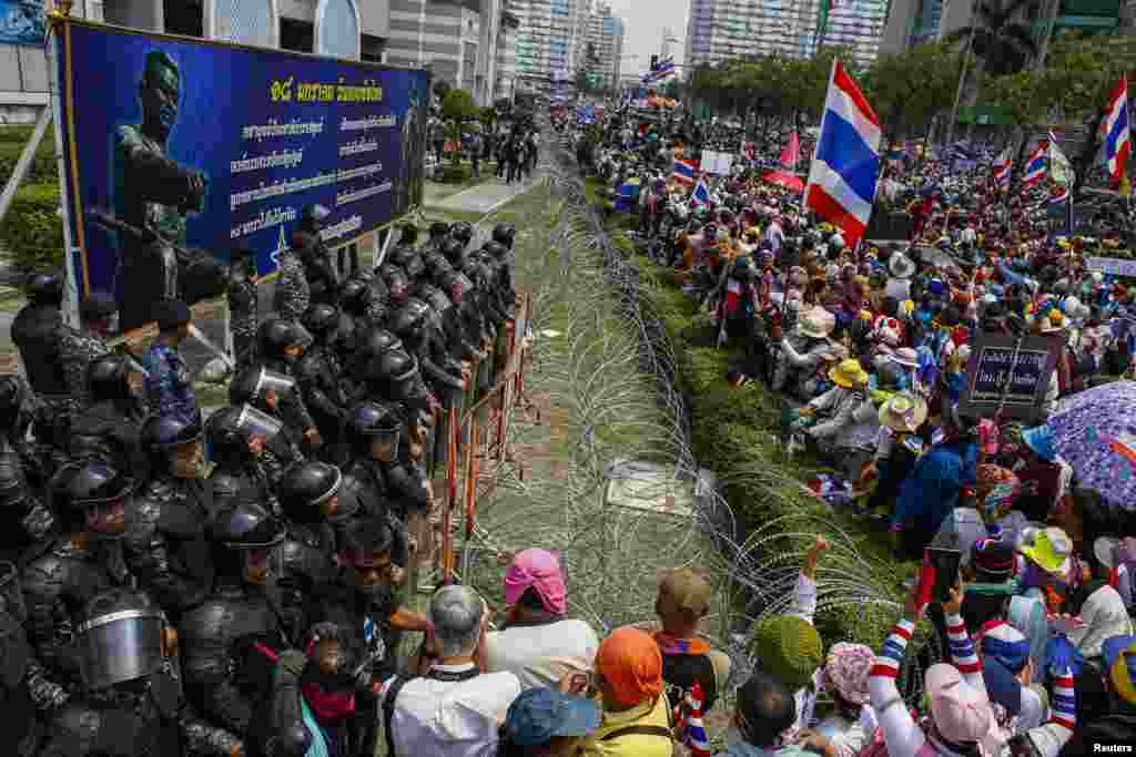 Anti-government protesters gather as Thai soldiers stand guard at a defense ministry compound serving as a temporary office for Thai Prime Minister Yingluck Shinawatra, Bangkok, Feb. 19, 2014. 