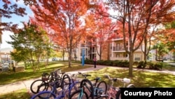 A student walks out of student housing towards a line of bicycles on the University of Tulsa campus.