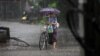 ရန်ကုန်မြို့မှာ မိုးရွာနေချိန် စက်ဘီးတွန်း သွားနေတဲ့ အမျိုးသမီး တဦး (ဇွန် ၂၉၊ ၂၀၁၉)