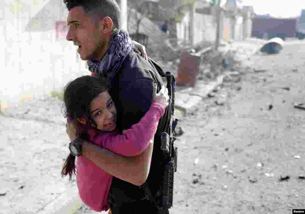 Seorang anggota pasukan Irak menggendong anak perempuan yang terluka akibat bom mobil ISIS yang meledak di distrik Tahrir, Mosul.
