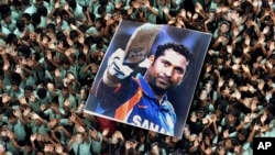 FILE - Indian students hold a large poster of Indian cricketer Sachin Tendulkar after Tendulkar batted for his landmark 100th century, Mar. 16, 2012.