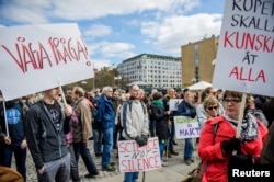 FILE - Demonstrators hold placards during the March for Science Stockholm manifestation at Medborgarplatsen square in Stockholm, Sweden, April 22, 2107.