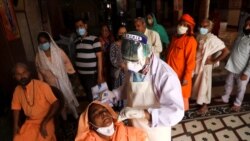 A healthcare worker wearing personal protective equipment (PPE) collects a swab sample from a female Sadhu or a Hindu holy woman amidst the spread of the coronavirus disease (COVID-19), at a temple in New Delhi, India March 30, 2021.