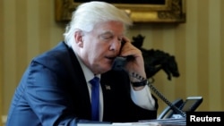 FILE - President Donald Trump conducts a phone call in the Oval Office at the White House in Washington, Jan. 28, 2017.